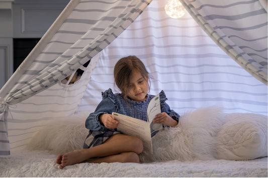 Child reading in our Striped Cabin Dreams Bed Tent.