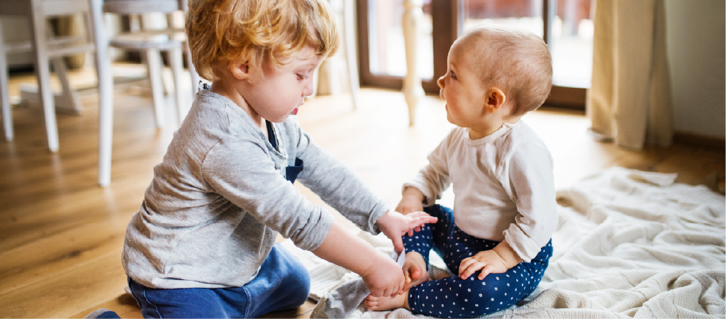 A baby and toddler interacting together