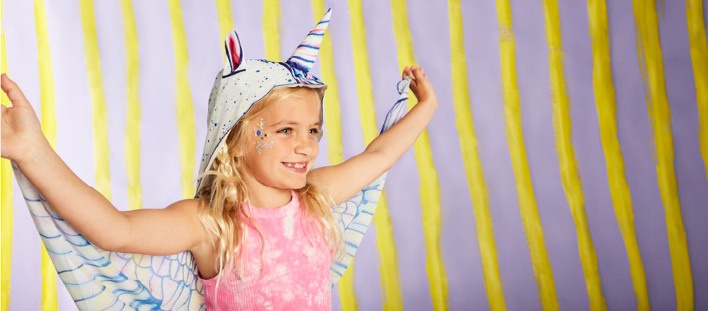 A kid playing while wearing unicorn costume.