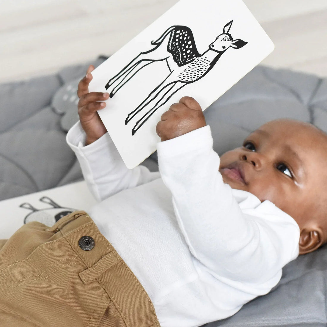 A baby holding a deer art card.