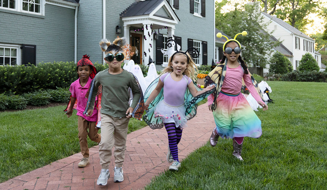 Four children in Halloween costumes walking down a brick path.