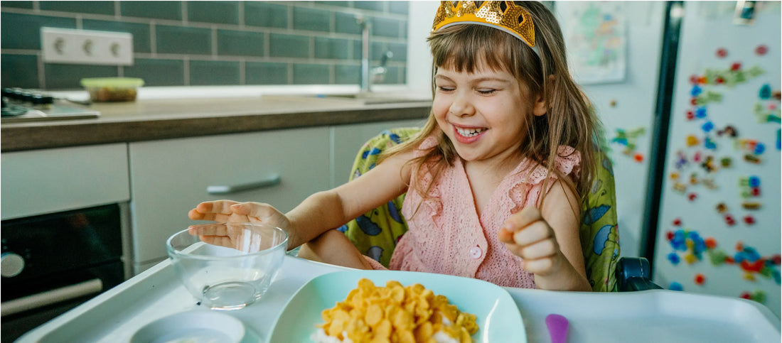 Girl with a paper tiara smiling and enjoying "kid dinner".